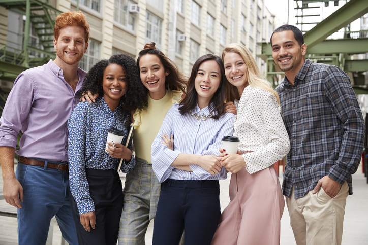 Six young adult coworkers standing outdoors, group portrait